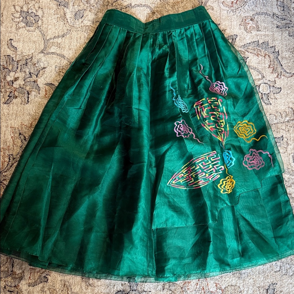Green pleated chiffon skirt with embroidered floral and geometric designs.